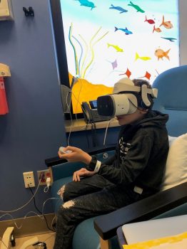 A child wearing a virtual reality headset while sitting on a hospital exam table