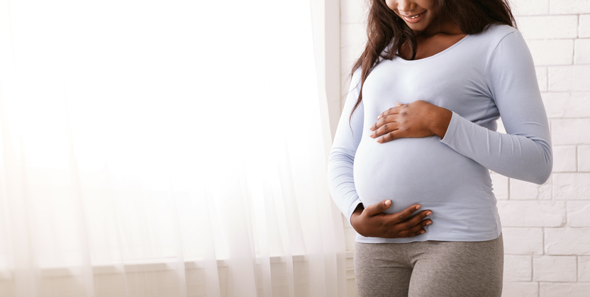 Pregnant woman smiles as she looks down at her stomach