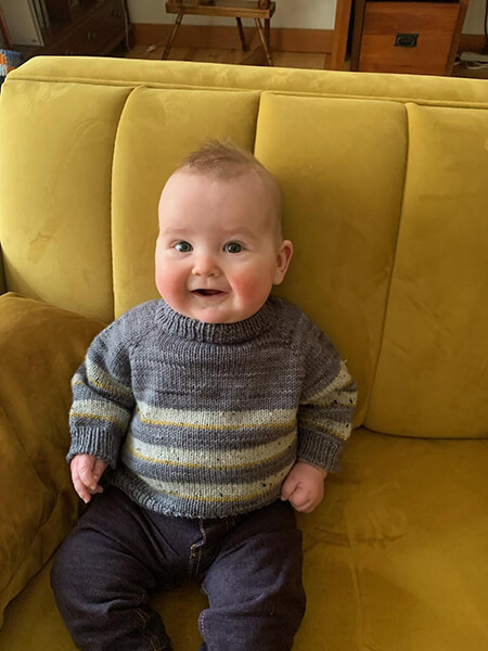 A smiling baby sitting on a couch