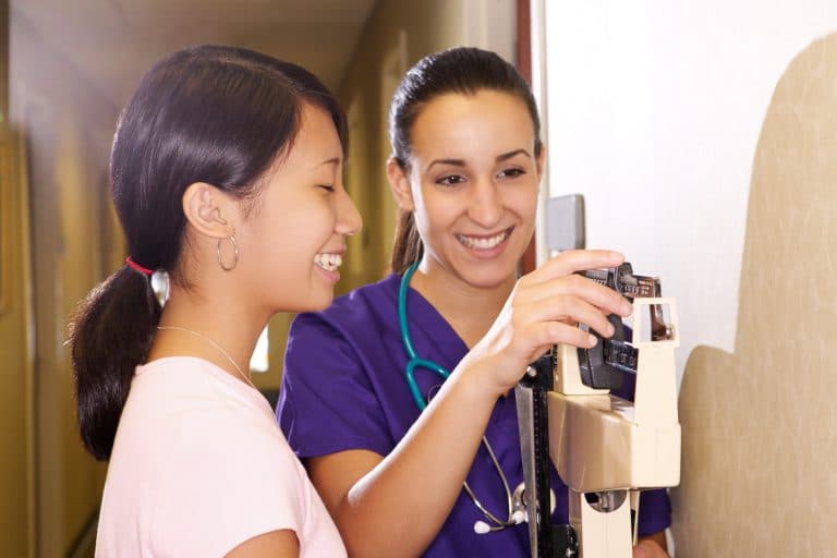 Young woman is weighed by a nurse.