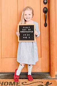 a girl poses with a 5th birthday sign