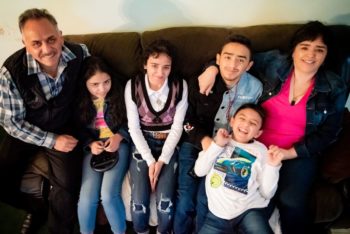 A family of six sit on a couch