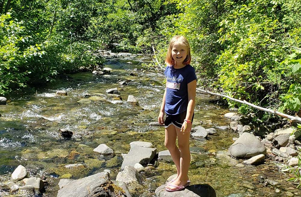 A girl poses by a stream