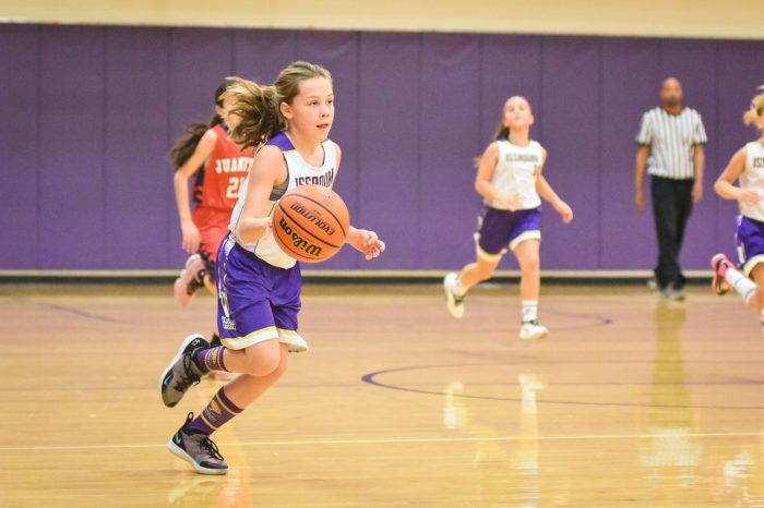 a girl dribbling a basketball in a game