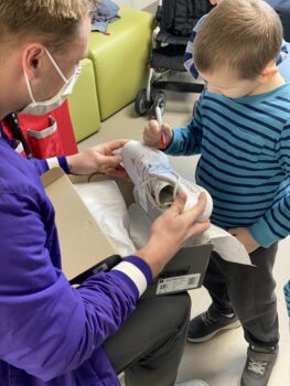 A little boy decorates a pair of cleats held by a baseball player