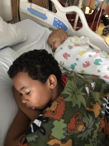 Two brothers sleep next to each other on a hospital bed 