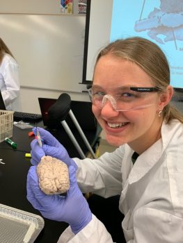 a teen wearing goggles and a lab coat in a science lab