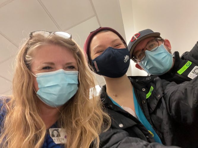 A family smiles in a selfie while wearing masks