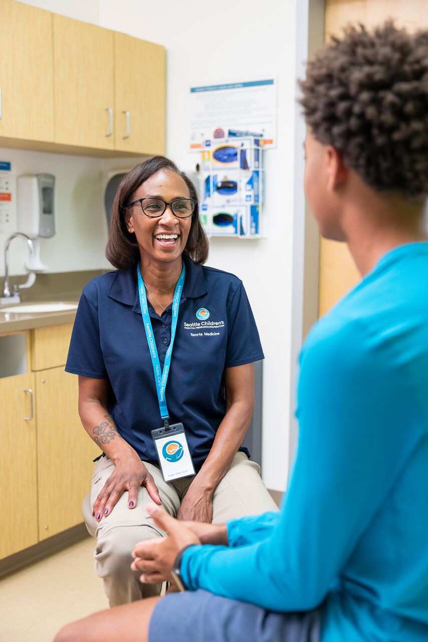 A female Seattle Children's doctor smiles as she interacts with her patient in an exam room