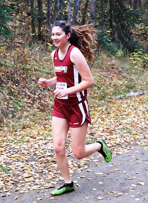 A teen girl running outside in a track uniform