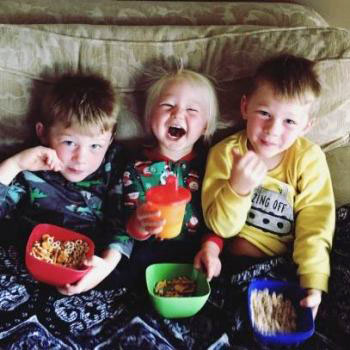 Three boys eating snacks on a couch