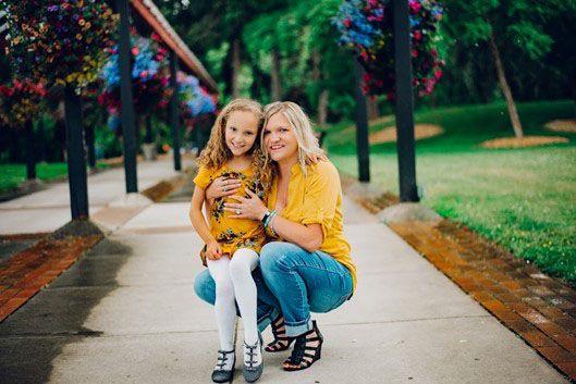 A mother and daughter pose for the camera outside