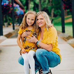 A mother and daughter pose for the camera outside