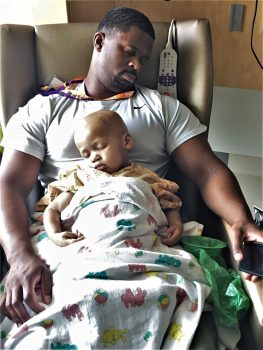 son and dad nap together in a chair in their hospital room