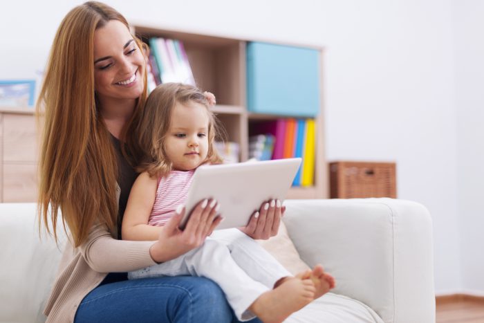 A mother and child look at an ipad together.