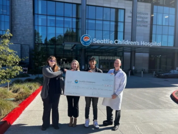 A group of four people pose with an oversized check