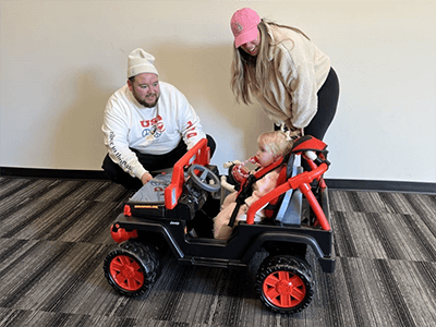 Toddler girl and her parents in a GoBabyGo car