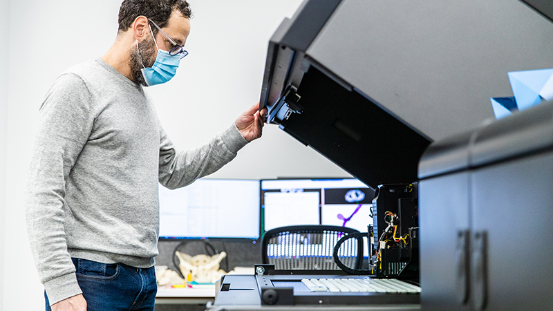 Team member in mask working at the 3D printer