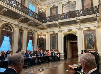 A group of cancer researchers sit around large wooden tables having a conversation about cancer