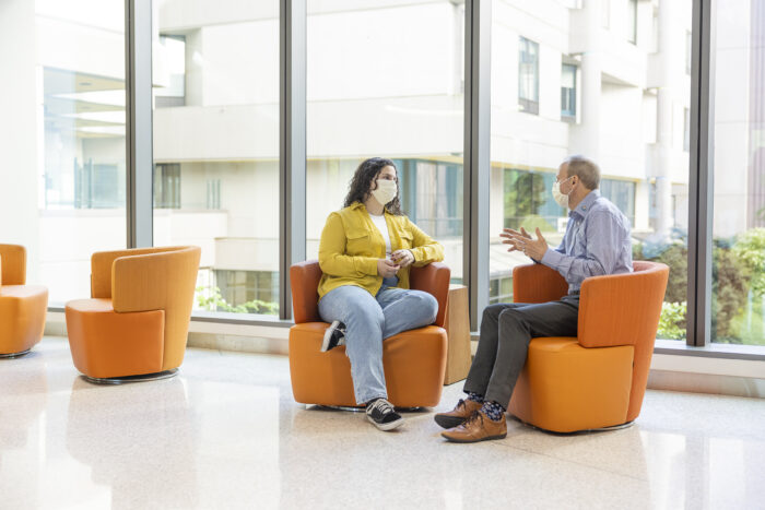 A young woman sits in Seattle Children's Hospital and speaks to a doctor