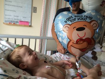 a toddler smiles in his hospital bed