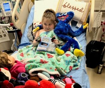 A little girl in her hospital bed shows her unique art creation