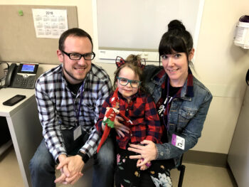 A little girl sits with her mother and father on either side of her