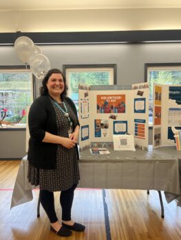 a woman standing at a table with a presentation board