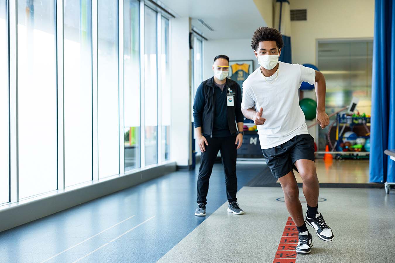 A patient runs down a hallway as a Seattle Children's provider watches