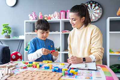 A woman helps a boy with a task at a table