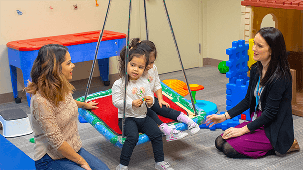 A Seattle Children's emplyoee plays with kids in a play room