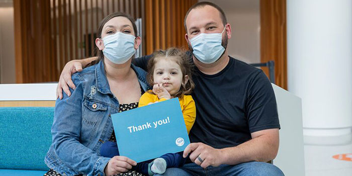 A family holds a sign that reads "Thank you!"