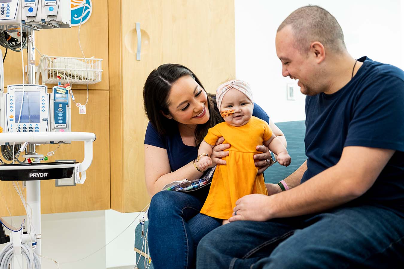 A mother and father hold a baby in a hospital room