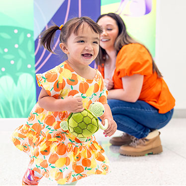 A girl holding a stuffed turtle runs in a hospital