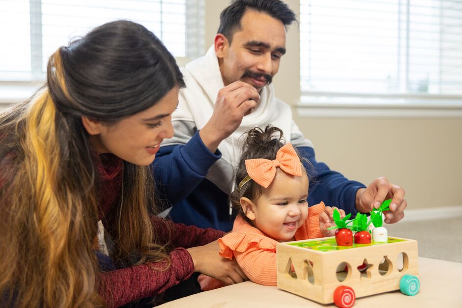 A father and mother play with their baby girl