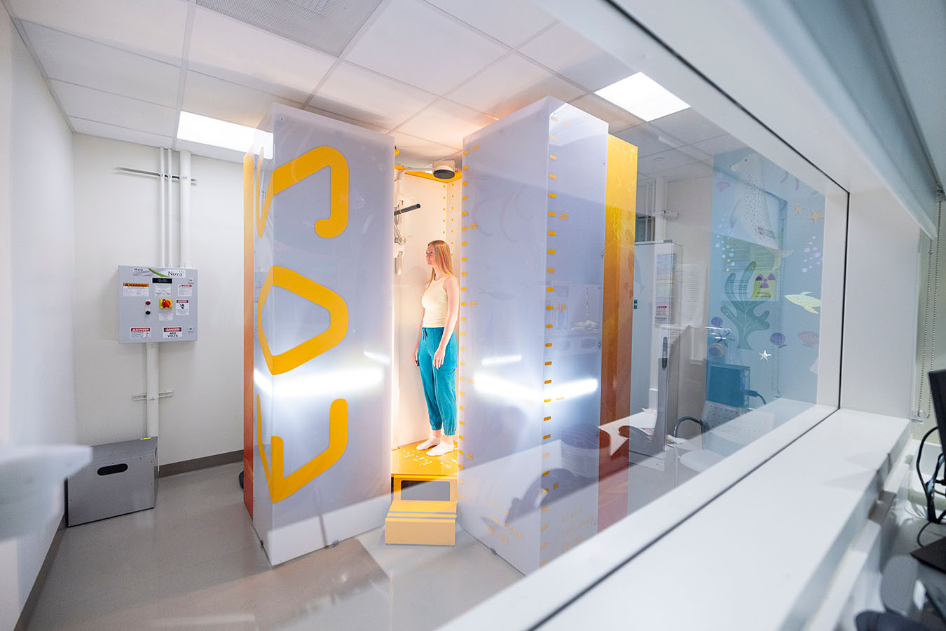 A teen girl stands in an x-ray machine at Seattle Children's