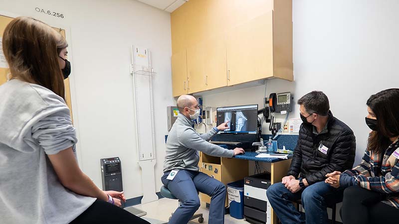 A patient and family look at an x-ray of a fractured bone presented on a computer screen by a Seattle Children's provider