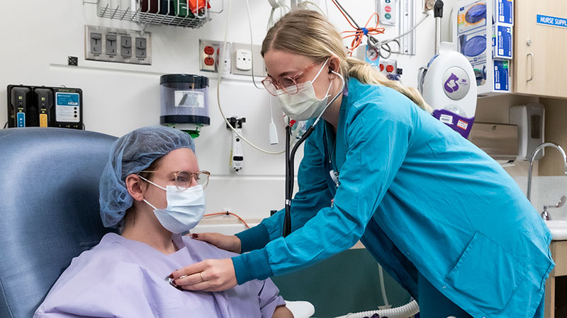 A Seattle Children's provider checks the heartbeat of a surgery patient.