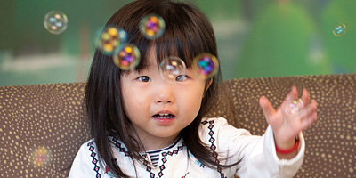 A girl reaches toward floating bubbles