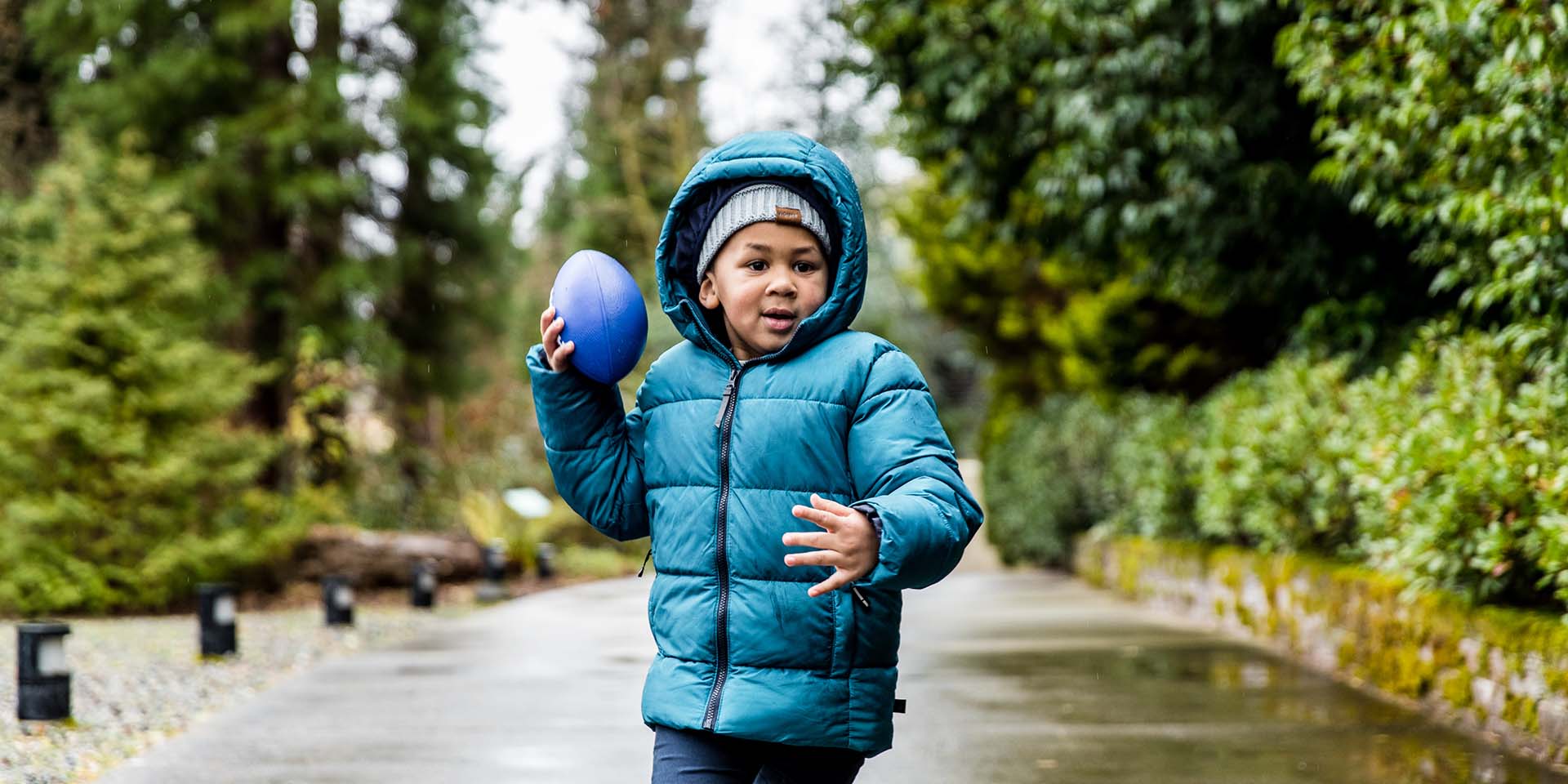 A boy in a winter coat holds a small football