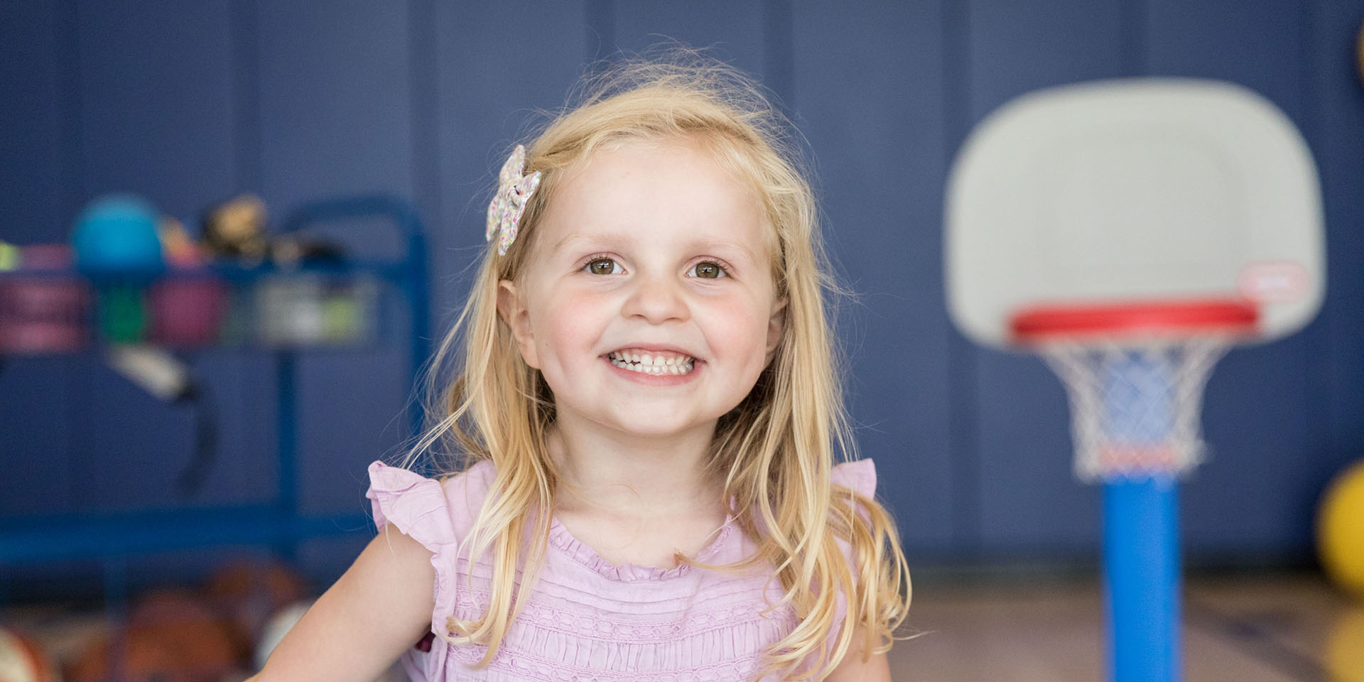 A girl stands in front of a toy basketball hoop