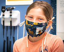 a smiling girl wearing a mask over her nose and mouth