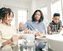 A mother and children eat a meal together