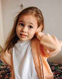 A girl with her hand against her ear