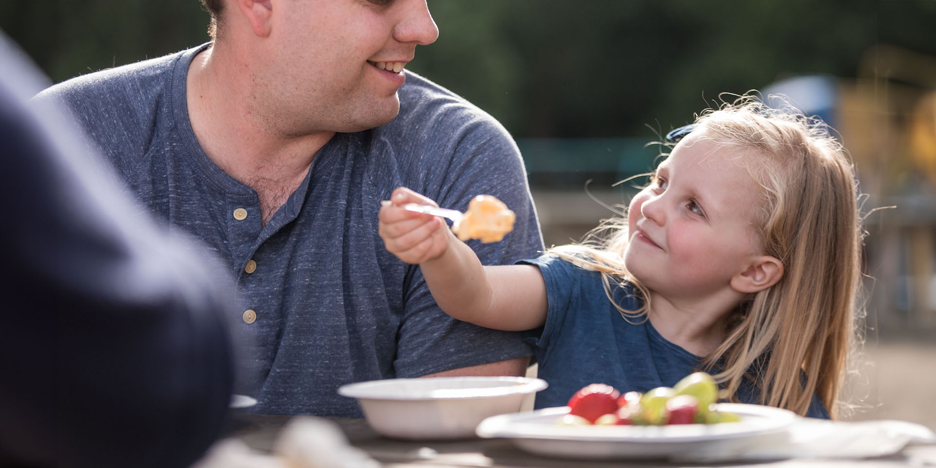 A father watches his daughter eat