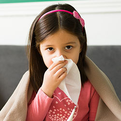 A girl blows her nose into a tissue