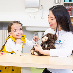 A girl sits at a table with a Seattle Children's employee