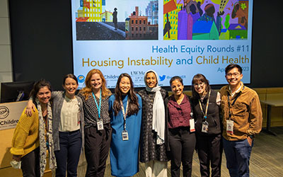 Residents pose for a picture in front of a projection of a Health Equity presentation