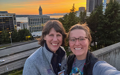 To women take a selfie in front of a sunset