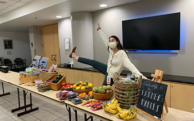 A resident poses behind tables with food